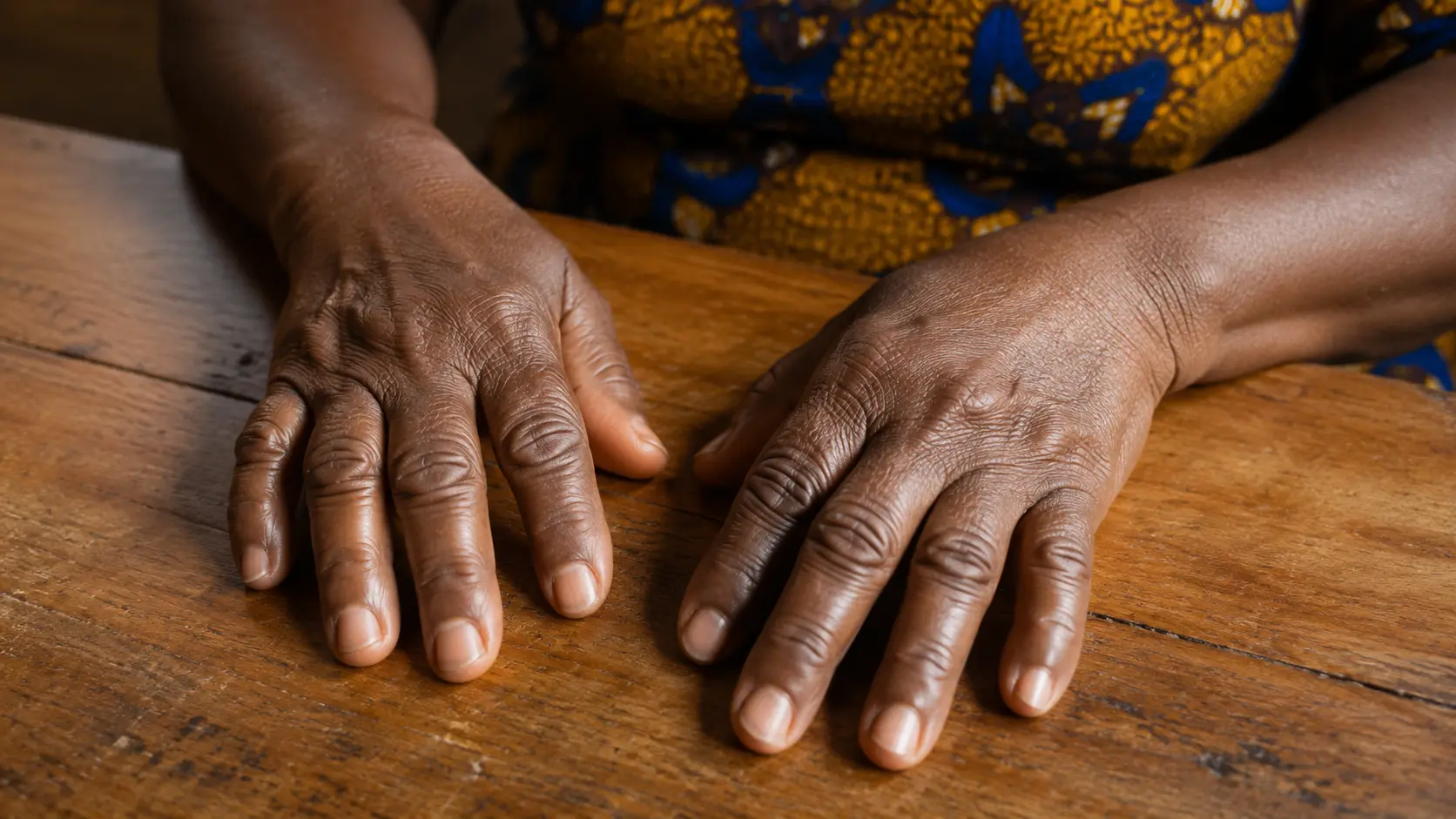 Mains d'une personne âgée posées sur une table en bois